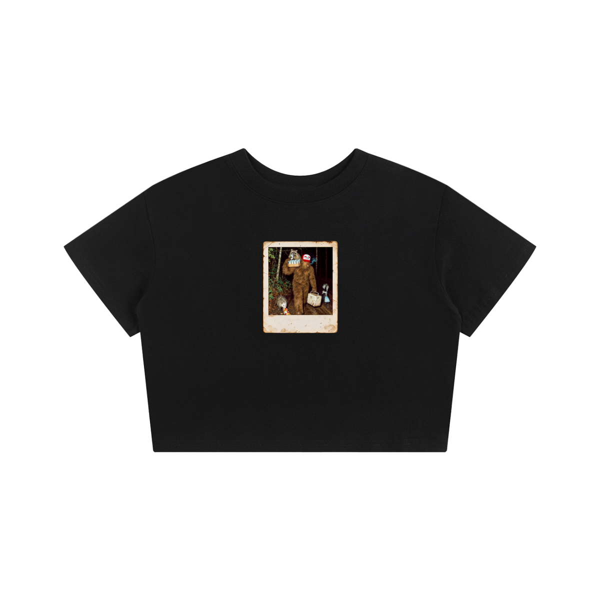A black short-sleeve crop top t-shirt featuring a vintage-style Polaroid photo graphic on the chest, displayed against a solid white background.