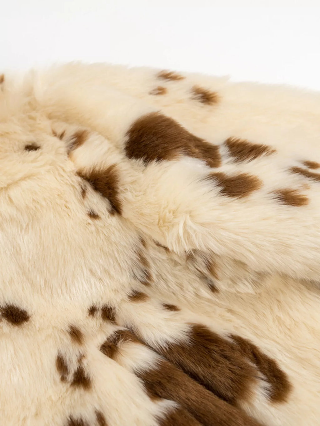 Close-up of a cowhide rug with brown spots on a white background