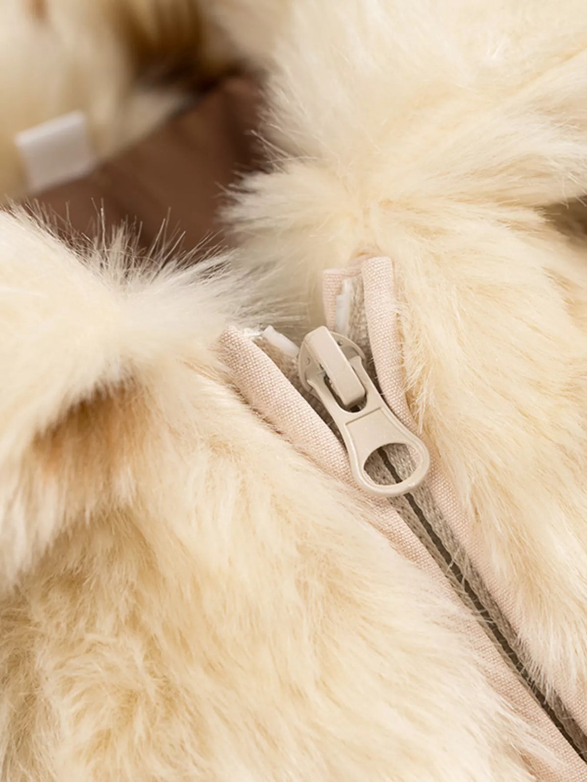 Close-up of a beige fur coat with a zipper
