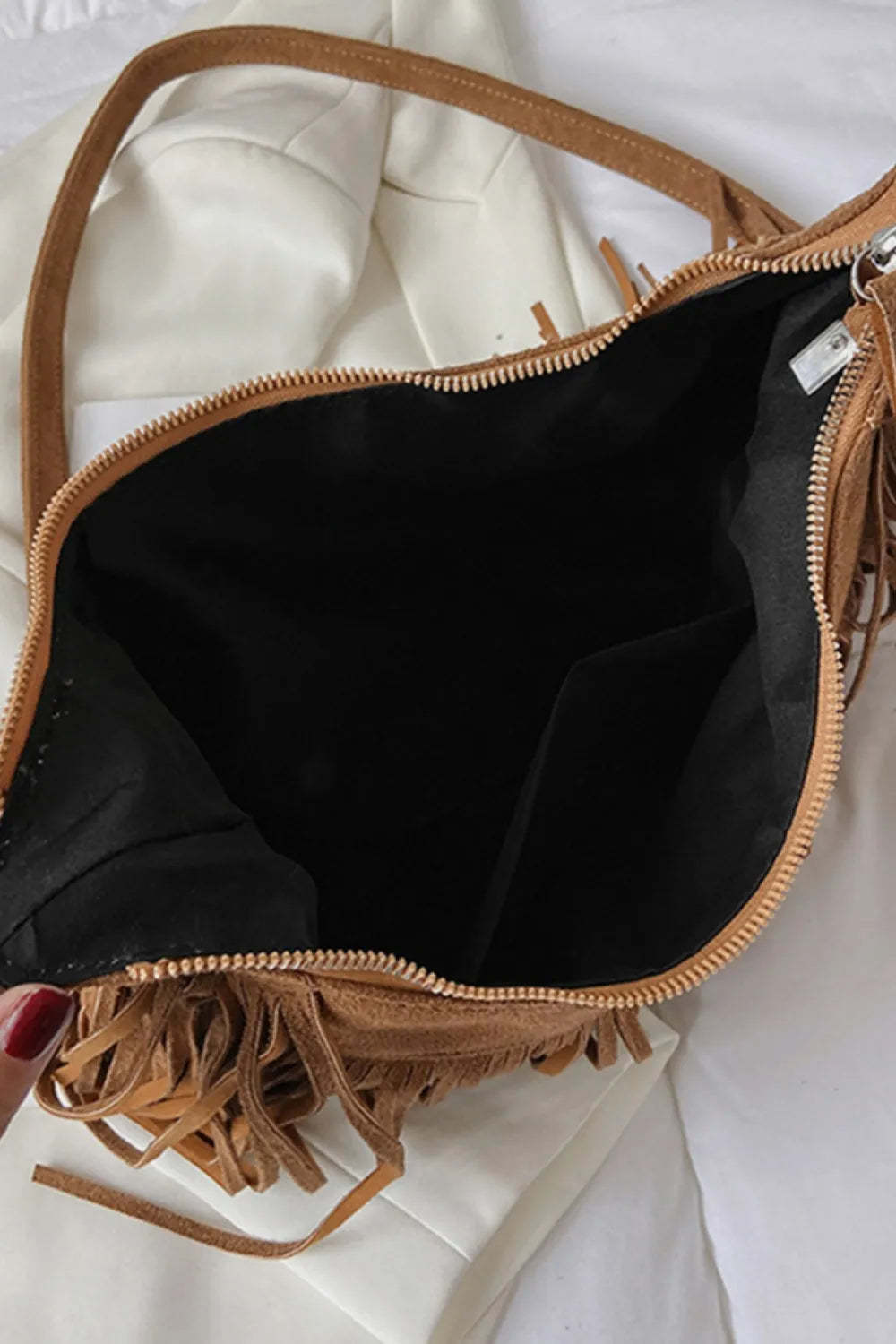 Brown leather handbag with fringe details on a white background