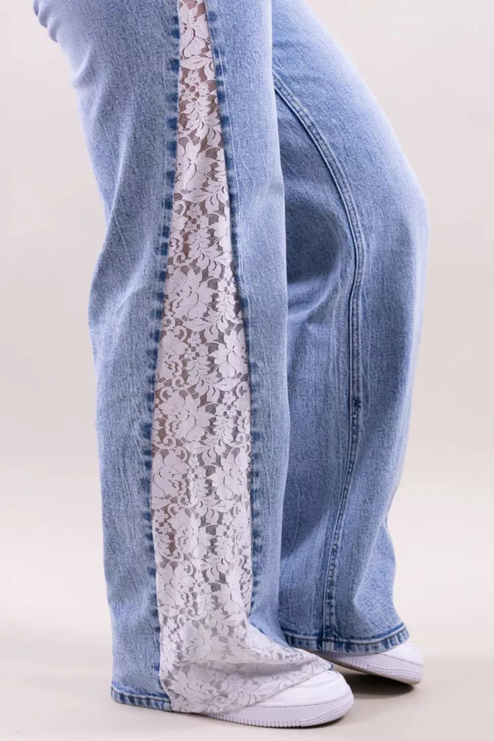 Light blue jeans with lace trim on a white background