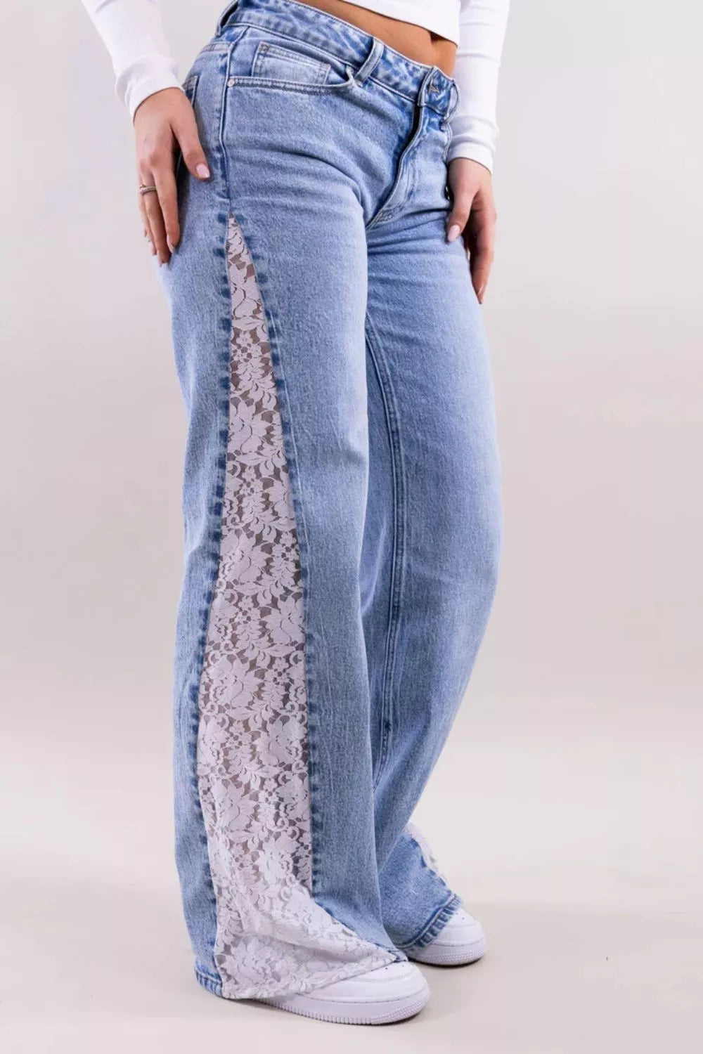 Blue jeans with lace detailing on a plain background