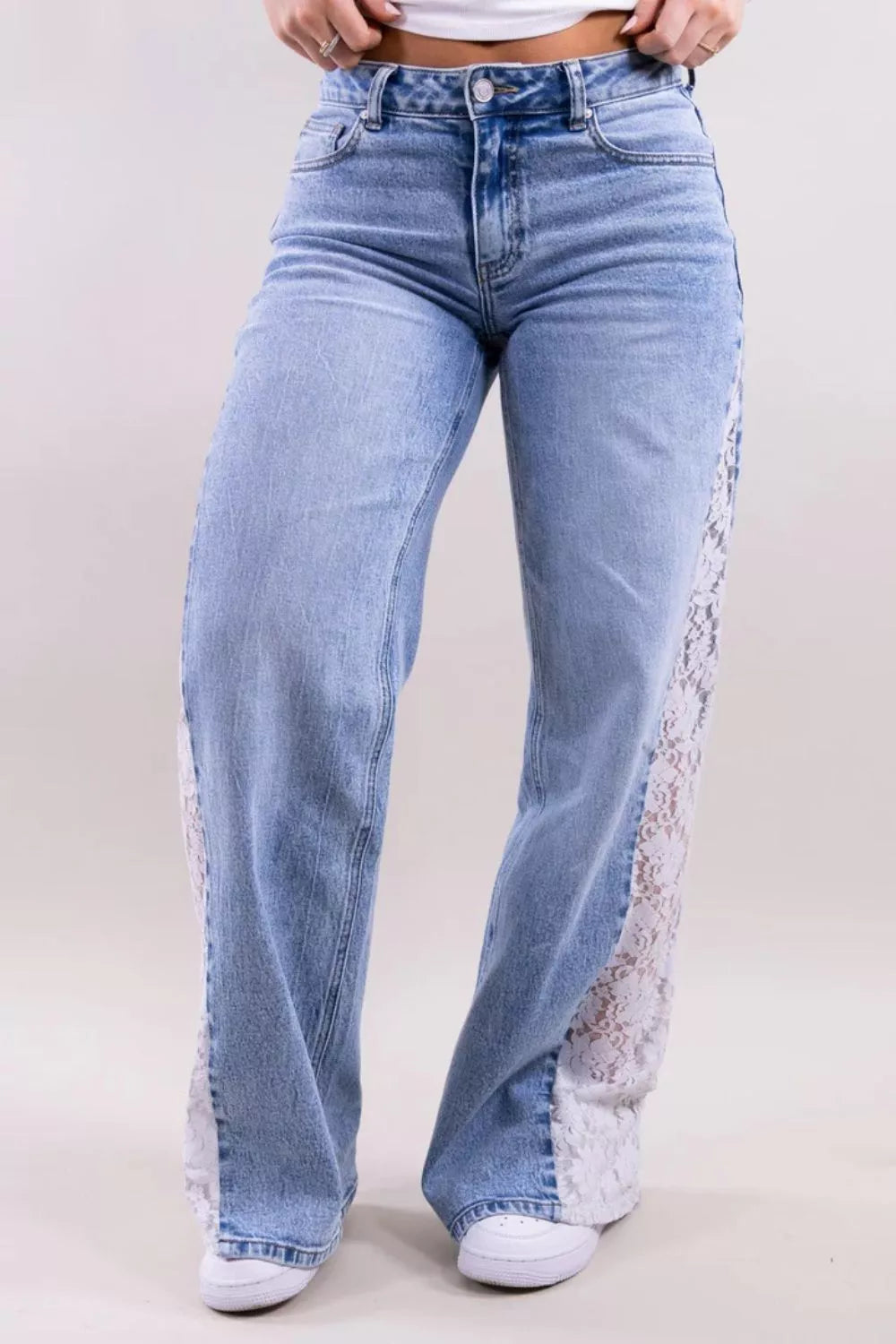 Light blue wide-leg jeans with white lace panels running down the outer sides of the legs, shown on a model from the waist down against a plain light background.
