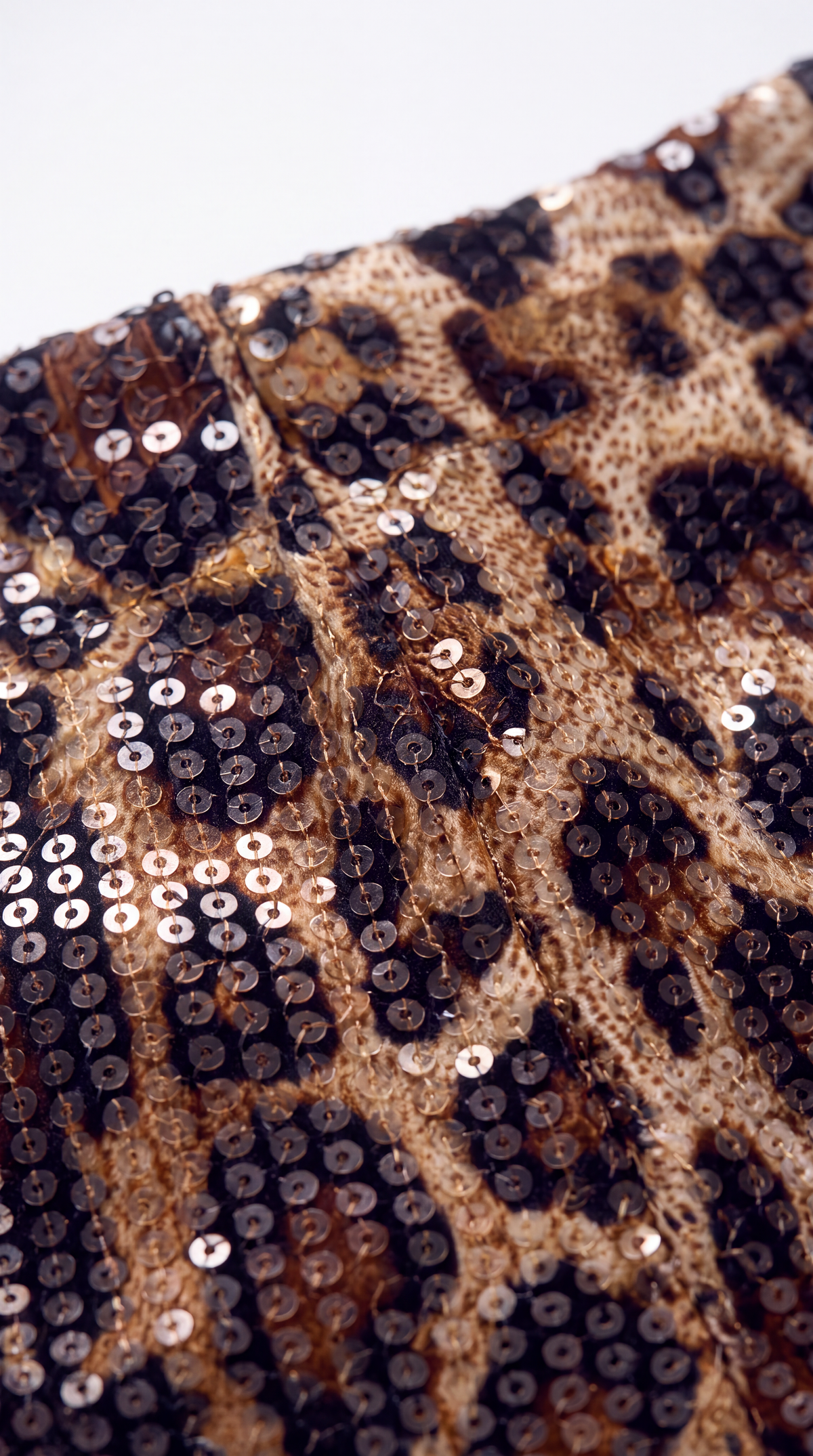 Close-up of a leopard print sequin fabric with black, brown, and beige tones.