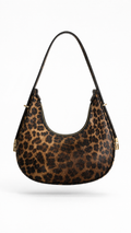A leopard print shoulder bag with a curved crescent shape, featuring a brown and black animal pattern, gold-tone hardware, and a thin black shoulder strap, shown against a plain white background.