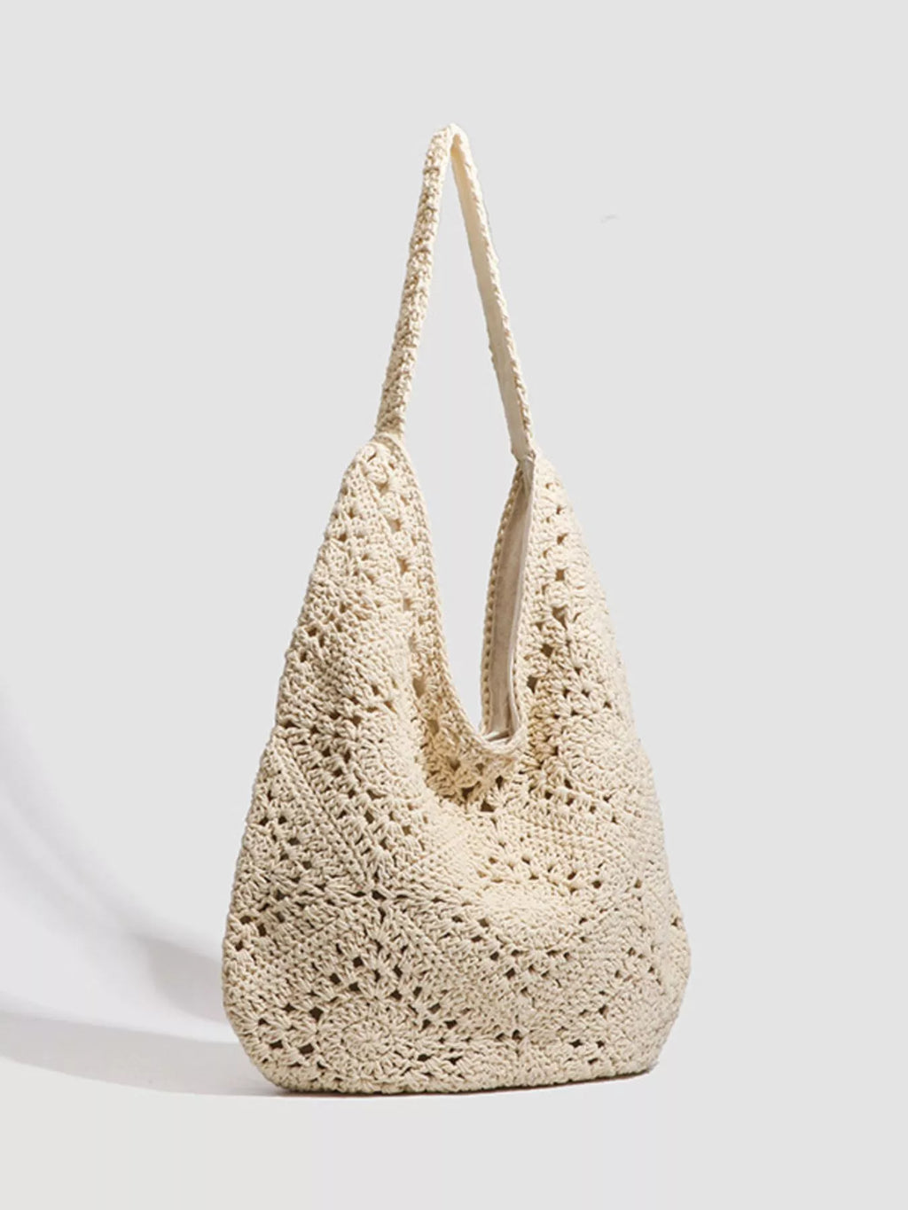A cream-colored crochet shoulder bag with a textured openwork pattern and a single shoulder strap, photographed on a light gray background.