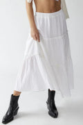 Person wearing a white skirt and black ankle boots on a white background