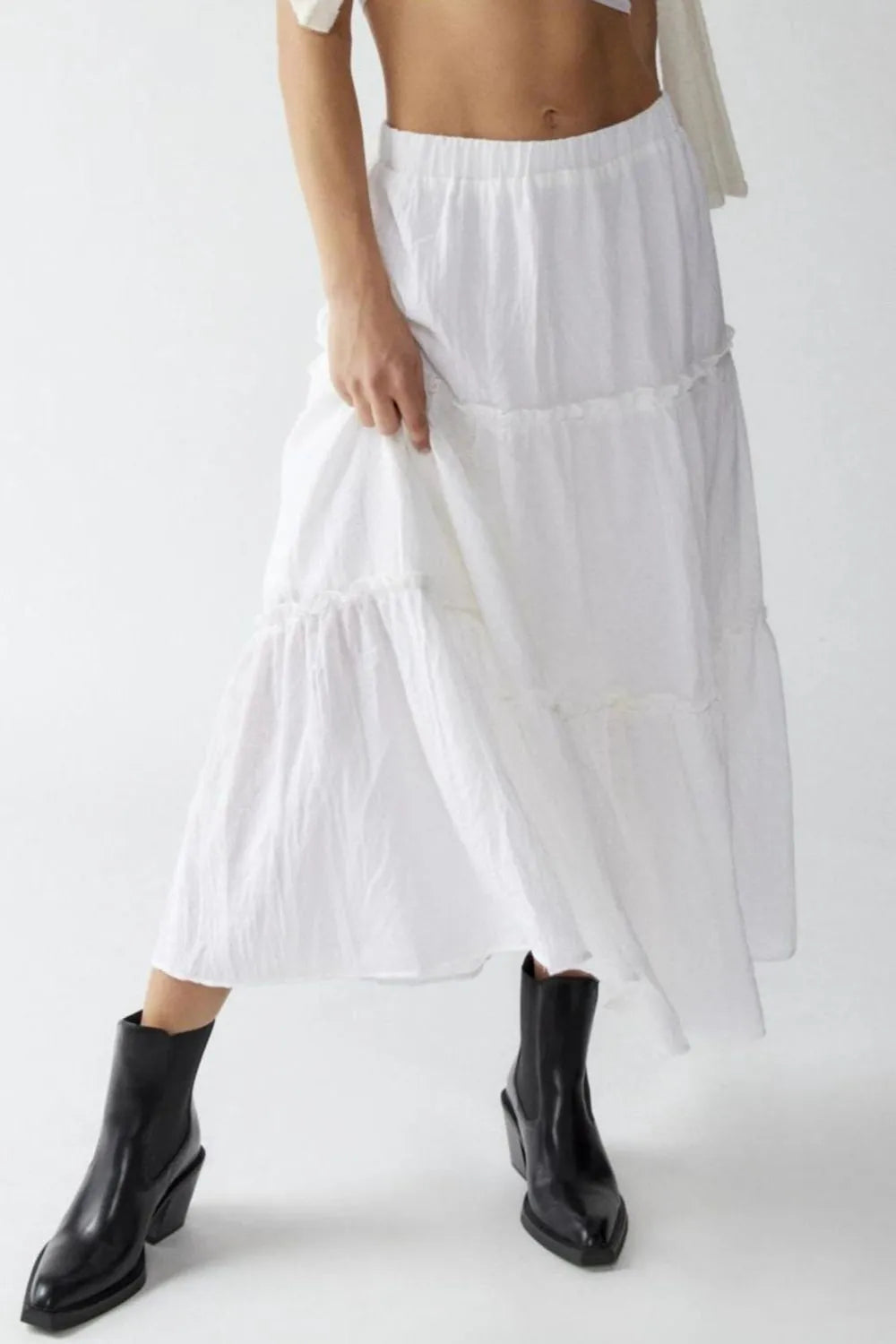 Person wearing a white skirt and black ankle boots on a white background